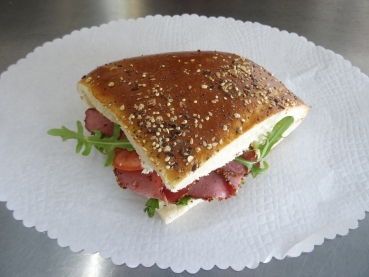 Pide-Brot gefüllt mit: Rind-Pastrami, Rucola und Tomaten an Senf-Zitronen-Sauce. Kantenlänge ca. 15 cm.