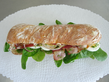 Panini gefüllt mit: geröstetem Speck, Zwiebelstreifen, Eier-Scheiben, Nüssli-Salat, Schnittlauch an Haus-Sauce. ca. 20 cm.